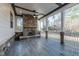 Screened-in porch featuring a stone fireplace, wood-look flooring, and natural light at 4009 Yates Mill Pond Rd, Raleigh, NC 27606