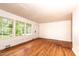 Sunlit living room boasts hardwood floors, wood paneling, and large windows framing the outdoors at 420 Peyton St, Raleigh, NC 27610
