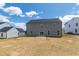 Backyard with a gray house, patio, sliding glass doors, and blue sky at 50 Rosewood Ln, Youngsville, NC 27596