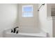 Bright white bathtub with black fixtures and natural light from the window above at 50 Rosewood Ln, Youngsville, NC 27596