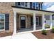 Close-up of the front door with white pillars, black shutters, and decorative landscaping at 50 Rosewood Ln, Youngsville, NC 27596