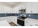 Modern kitchen features stainless steel appliances, white cabinets, dark backsplash, and quartz countertops at 50 Rosewood Ln, Youngsville, NC 27596