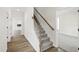 Carpeted staircase with wooden banister and white risers, open to a room with hardwood floors at 50 Rosewood Ln, Youngsville, NC 27596