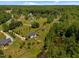 Wide aerial view of a residential area with single-Gathering homes, mature trees, and a tranquil pond at 5013 W Pool Rd, Rougemont, NC 27572