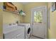 Well-lit laundry room equipped with a washer, dryer, storage shelves, and convenient exterior access at 5013 W Pool Rd, Rougemont, NC 27572