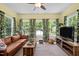Bright living room featuring large windows, a brown sofa, plants, and a cozy atmosphere at 5013 W Pool Rd, Rougemont, NC 27572