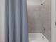 Bathroom with a shower-tub combo with light gray tile walls and gray shower curtain at 5145 Landguard Dr, Raleigh, NC 27613