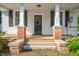 Charming front door with brick and concrete accents, flanked by black shuttered windows at 5299 Momeyer Way, Nashville, NC 27856