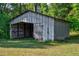Exterior of a rustic, aged metal shed, offering a glimpse into its country charm amidst lush greenery at 5299 Momeyer Way, Nashville, NC 27856