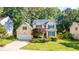 Attractive yellow two-story home features blue shutters, lush landscaping, and a well-maintained lawn at 5417 Harrington Grove Dr, Raleigh, NC 27613