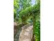 Stone pathway through a lush garden with flowering vines creating a serene and inviting outdoor space at 5417 Harrington Grove Dr, Raleigh, NC 27613
