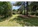 Private backyard featuring lush green grass and mature shade trees at 5812 N Beaver Ln, Raleigh, NC 27604