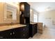 This updated bathroom has double sinks with granite countertops, dark wood cabinets, and a tiled tub at 5812 N Beaver Ln, Raleigh, NC 27604
