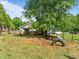 Large fenced backyard with mature trees, play structures, and a tire obstacle course, ideal for pets and outdoor activities at 6200 Oliver Creek Pkwy, Holly Springs, NC 27540