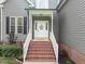 Inviting front entrance with brick steps and white railings, creating a welcoming and charming curb appeal at 6200 Oliver Creek Pkwy, Holly Springs, NC 27540