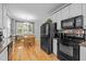 Charming eat-in kitchen featuring white cabinetry, granite counters, black appliances, and hardwood flooring at 6200 Oliver Creek Pkwy, Holly Springs, NC 27540