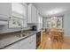 Well-lit kitchen with stainless sink, granite countertops, white cabinets, and adjacent dining area at 6200 Oliver Creek Pkwy, Holly Springs, NC 27540
