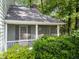 Charming home exterior featuring a screened porch bordered by lush greenery and manicured bushes at 6420 Dresden Ln, Raleigh, NC 27612