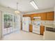 Practical kitchen area with wood cabinets, white appliances, and sliding glass doors at 649 Flaherty Ave, Wake Forest, NC 27587