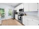 Bright kitchen features white cabinets, stainless steel appliances, and ample counter space and a door to outside at 6612 Rossford Ln, Durham, NC 27713