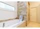 Spa-like bathroom featuring a soaking tub, stone accent wall, and glass-enclosed shower at 7501 Tipsy Sq, Wake Forest, NC 27587