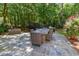 Outdoor stone patio with a dining table, chairs, grilling area, and wooded surroundings at 7501 Tipsy Sq, Wake Forest, NC 27587