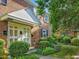 Inviting brick townhouse featuring a covered entrance, manicured landscaping and black window shutters at 945 St Marys St, Raleigh, NC 27605