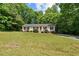 A charming single-story home nestled among lush trees and greenery with a sprawling front lawn at 1004 Candlewood Cir, Siler City, NC 27344