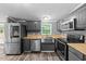 Updated kitchen features stainless appliances, gray cabinets, butcher block countertops, and wood-look flooring at 1004 Candlewood Cir, Siler City, NC 27344