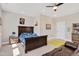Spacious bedroom with a dark wood bed frame, ceiling fan, and decorative accents on the walls at 101 Rostova Way, Holly Springs, NC 27540