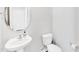 Clean and modern powder room featuring a pedestal sink, toilet, and stylish mirror at 103 Norris Creek Dr, Clayton, NC 27527