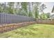 A lush, well-manicured lawn in the backyard, enhanced with a retaining wall and privacy fence for added seclusion at 120 Chapel Run Way, Chapel Hill, NC 27517