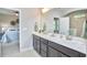 A bathroom featuring a double vanity with gray cabinets, white countertops, and mirrors, and a view into the bedroom at 120 Chapel Run Way, Chapel Hill, NC 27517