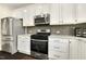 Modern kitchen features stainless steel appliances, white cabinets, and a stylish tile backsplash at 121 Martingale Dr, Holly Springs, NC 27540