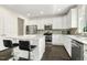 Modern kitchen with stainless steel appliances, gray backsplash, white cabinets, island with seating, and dark hardwood floors at 121 Martingale Dr, Holly Springs, NC 27540