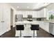 Modern kitchen with stainless steel appliances, gray backsplash, white cabinets, island with seating, and dark hardwood floors at 121 Martingale Dr, Holly Springs, NC 27540