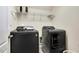 This laundry room is equipped with black washer, dryer, and overhead shelving at 121 Martingale Dr, Holly Springs, NC 27540