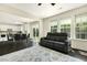Open concept living room featuring black leather seating, a view into the kitchen, and large windows at 121 Martingale Dr, Holly Springs, NC 27540