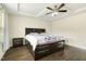 Well-lit bedroom with a ceiling fan, dark wood floors, bedside tables, and lots of storage in the bed frame at 121 Martingale Dr, Holly Springs, NC 27540