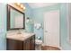 Powder blue bathroom has a wood vanity, toilet, mirror, and natural light at 125 Amesbury Ln, Cary, NC 27511