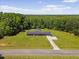 A charming single-story home features a long driveway, integrated garage and large manicured lawn surrounded by lush trees at 137 Vaiden Rd, Louisburg, NC 27549