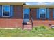 Close-up of a brick home's front entrance, showcasing a storm door and charming blue shutters at 137 Vaiden Rd, Louisburg, NC 27549