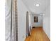 Long hallway featuring hardwood floors, white walls and neutral drapes over a glass paneled door at 137 Vaiden Rd, Louisburg, NC 27549