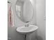 White pedestal sink and round mirror offer an elegant and functional design to the half bathroom at 1394 Southpoint Trl, Durham, NC 27713