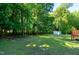 Large green backyard with mature trees, a utility shed, and a wood deck at 1443 Smokey Mountain Dr, Zebulon, NC 27597