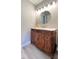 Bathroom features a wood vanity with white countertop, round mirror, and soft grey walls at 1443 Smokey Mountain Dr, Zebulon, NC 27597