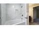 This bathroom features a marble tiled tub and shower, chrome fixtures, and a doorway to another room at 1443 Smokey Mountain Dr, Zebulon, NC 27597