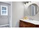 Bathroom features a wood vanity with white countertop, round mirror, and soft grey walls at 1443 Smokey Mountain Dr, Zebulon, NC 27597