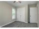 A small, unfurnished bedroom features neutral paint, carpet, a ceiling fan, one window, and a closet at 1443 Smokey Mountain Dr, Zebulon, NC 27597