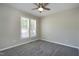 A small, unfurnished bedroom features neutral paint, carpet, a ceiling fan, and two windows at 1443 Smokey Mountain Dr, Zebulon, NC 27597